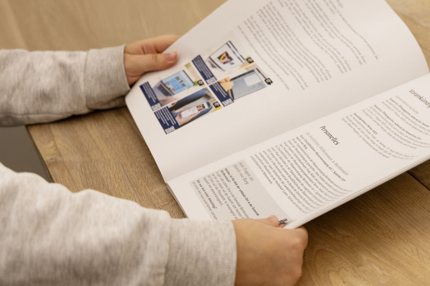 Eine Person in einem grauen Pullover liest eine Zeitschrift auf einem Holztisch. Die Zeitschrift enthält Text und Bilder zu Produkten und Anleitungen. Hände halten die Seiten offen.