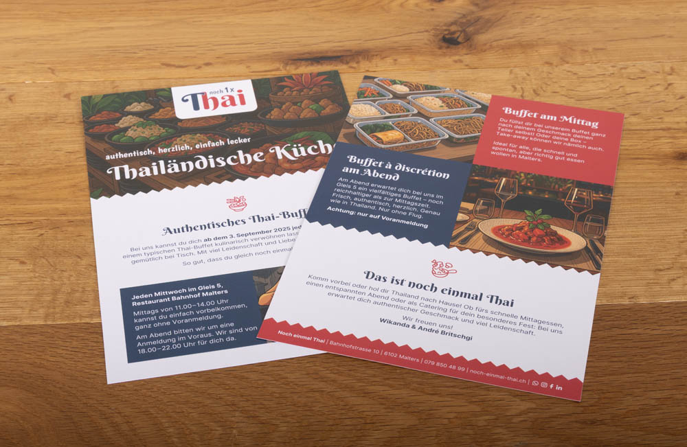 Zwei bunte Flyer für ein thailändisches Restaurant mit Abbildungen von thailändischen Gerichten, Speisekarten und Informationen zum Buffet, nebeneinander auf einem Holztisch. Der Text ist auf Deutsch.