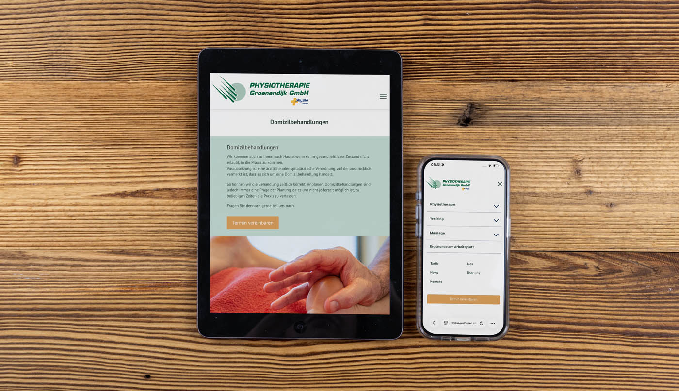 Ein Tablet und ein Smartphone, auf denen die Website der Physiotherapiepraxis „Physio-Wolhusen“ auf Deutsch angezeigt wird, liegen auf einer Holzunterlage. Auf dem Tablet ist eine Hand zu sehen, die behandelt wird, während auf dem Smartphone das Menü der Website angezeigt wird.